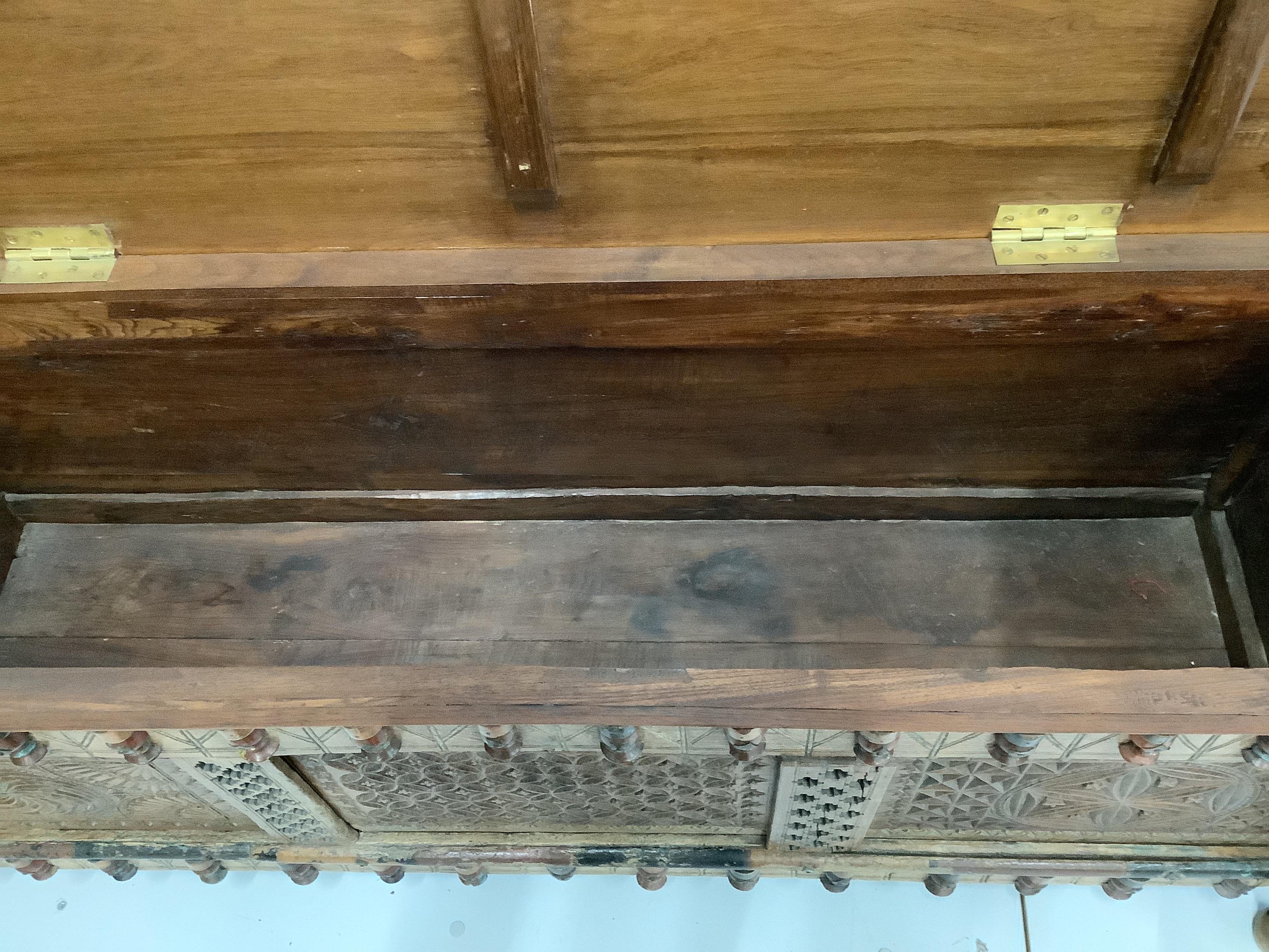 An Indian carved and panelled hardwood low chest, with figural motifs, width 148cm, depth 60cm, height 57cm.